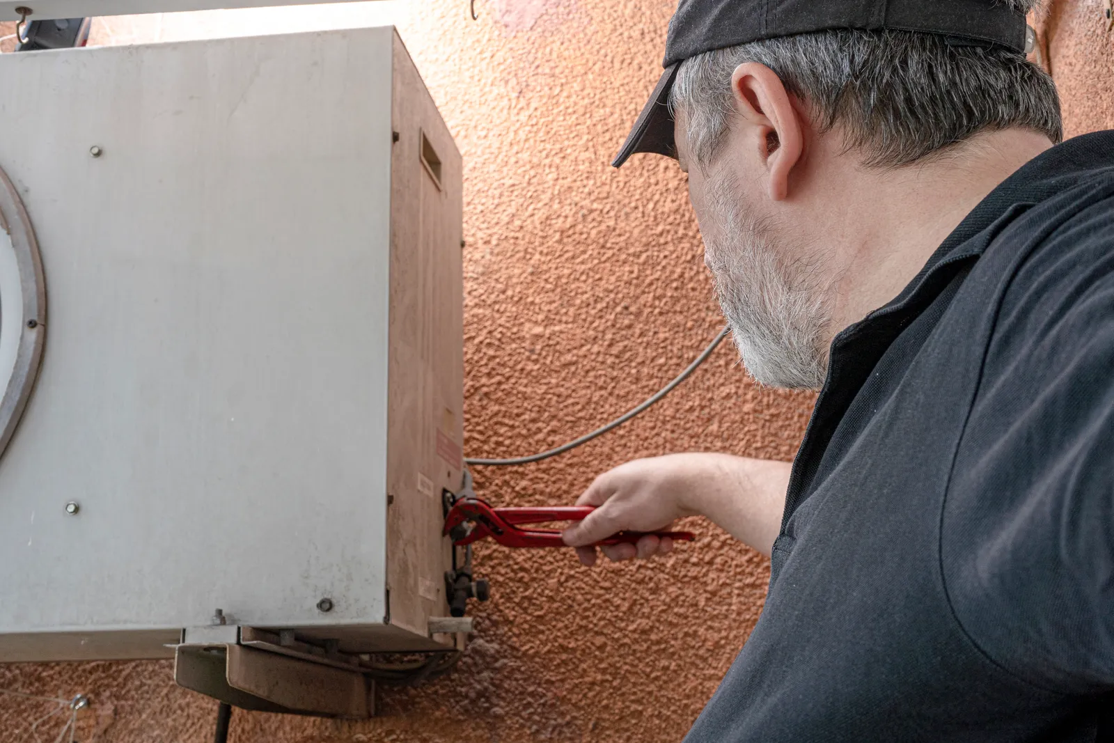 Technician mounting a new tankless water heater on a garage wall during an installation