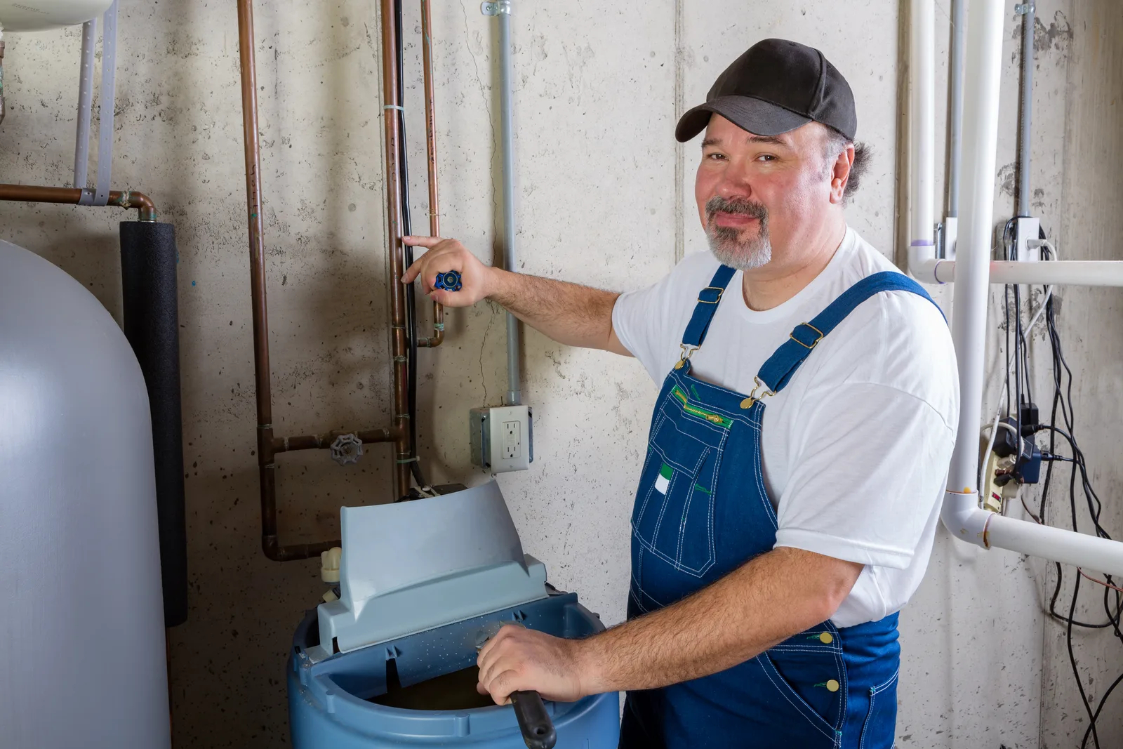 Water treatment technician installing a water softener system beside a home's main water line