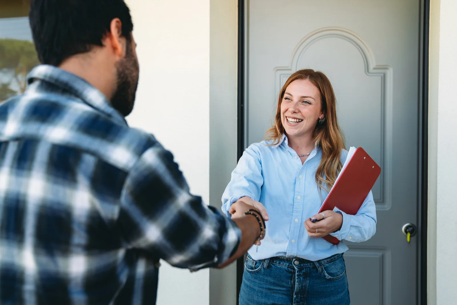 Cash home buyer shaking hands with a homeowner on the front steps of an as-is house after agreeing on an offer