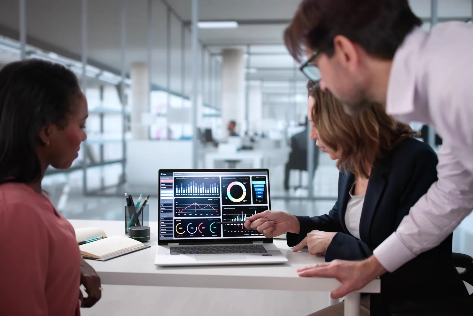 Wealth management software team reviewing a client portfolio dashboard and demo-pipeline metrics together at a laptop in their office