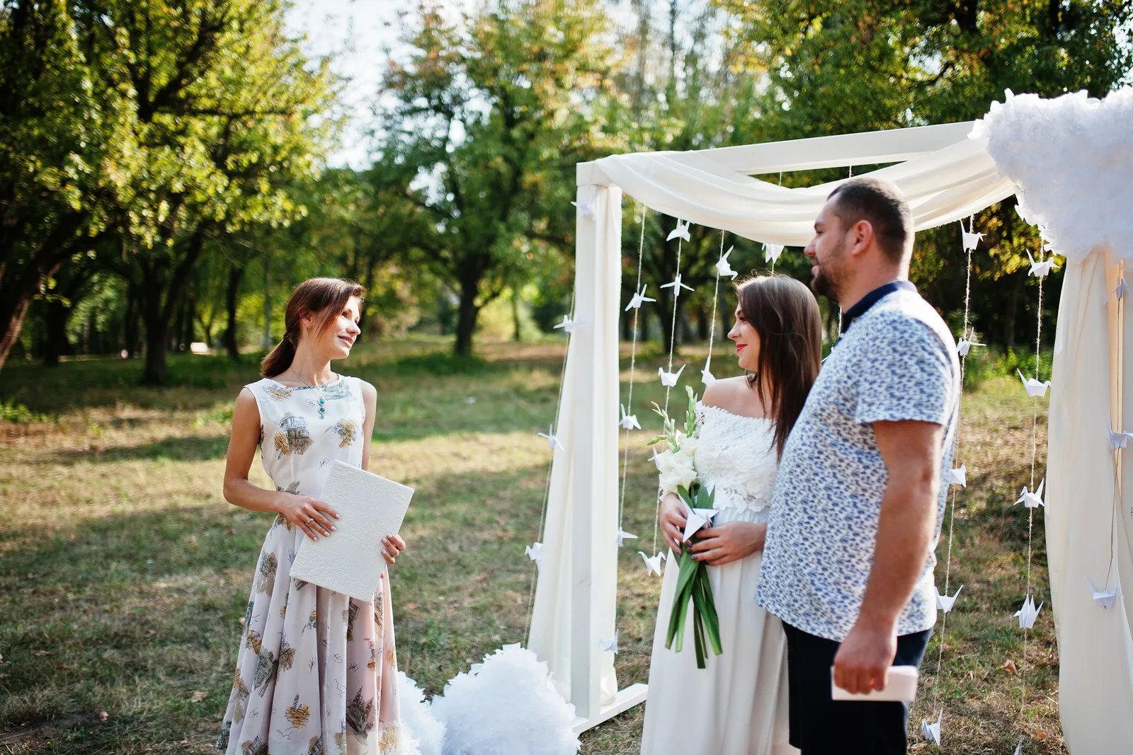 Wedding officiant reading vows to a smiling couple at the altar as guests look on