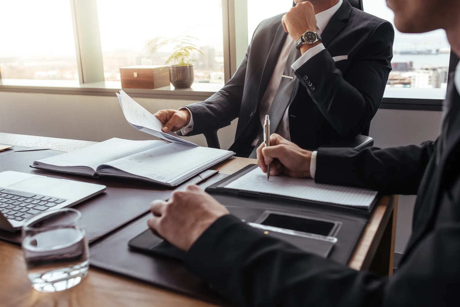 Defense attorney and client reviewing financial records and case documents at a conference table