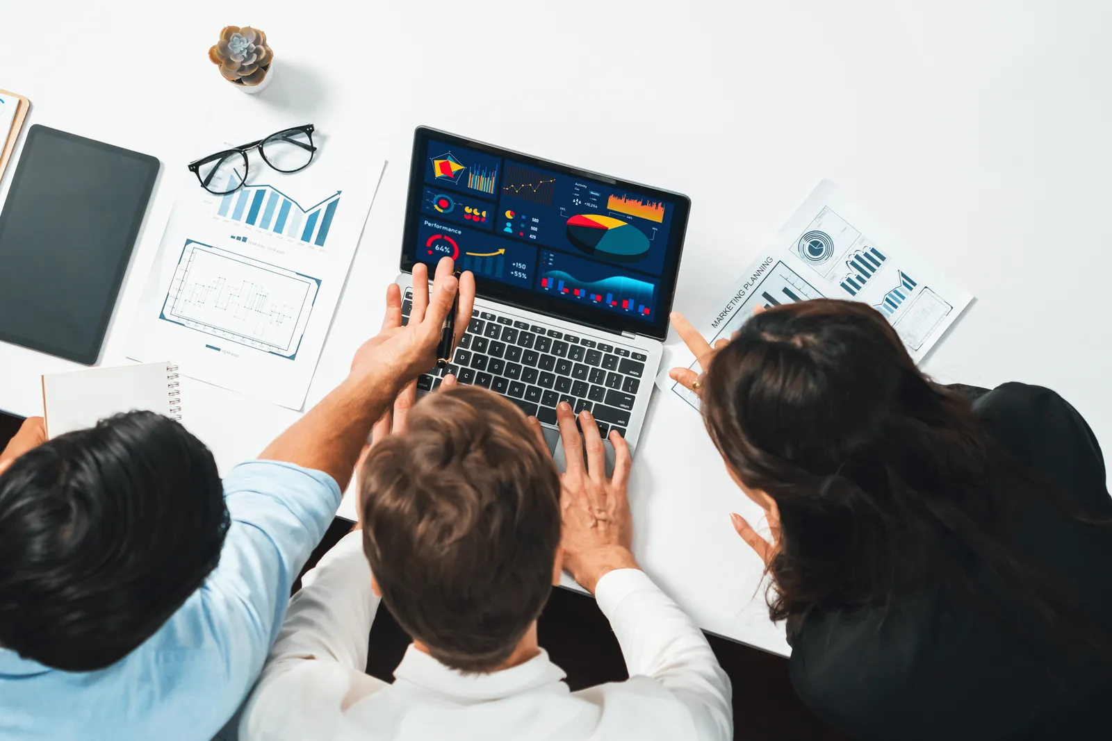 Software team reviewing partner-signup and reseller-activation dashboards together at a laptop in their office