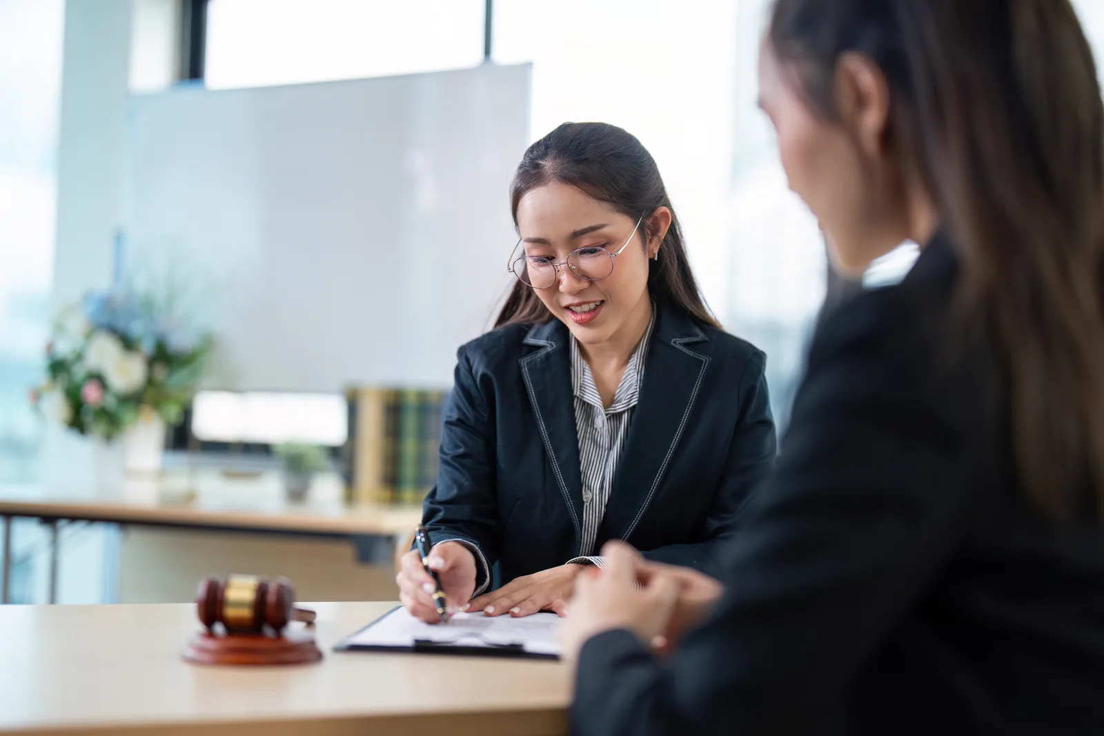 Wrongful death attorney sitting across from a grieving family at a law office conference table, reviewing case paperwork with them