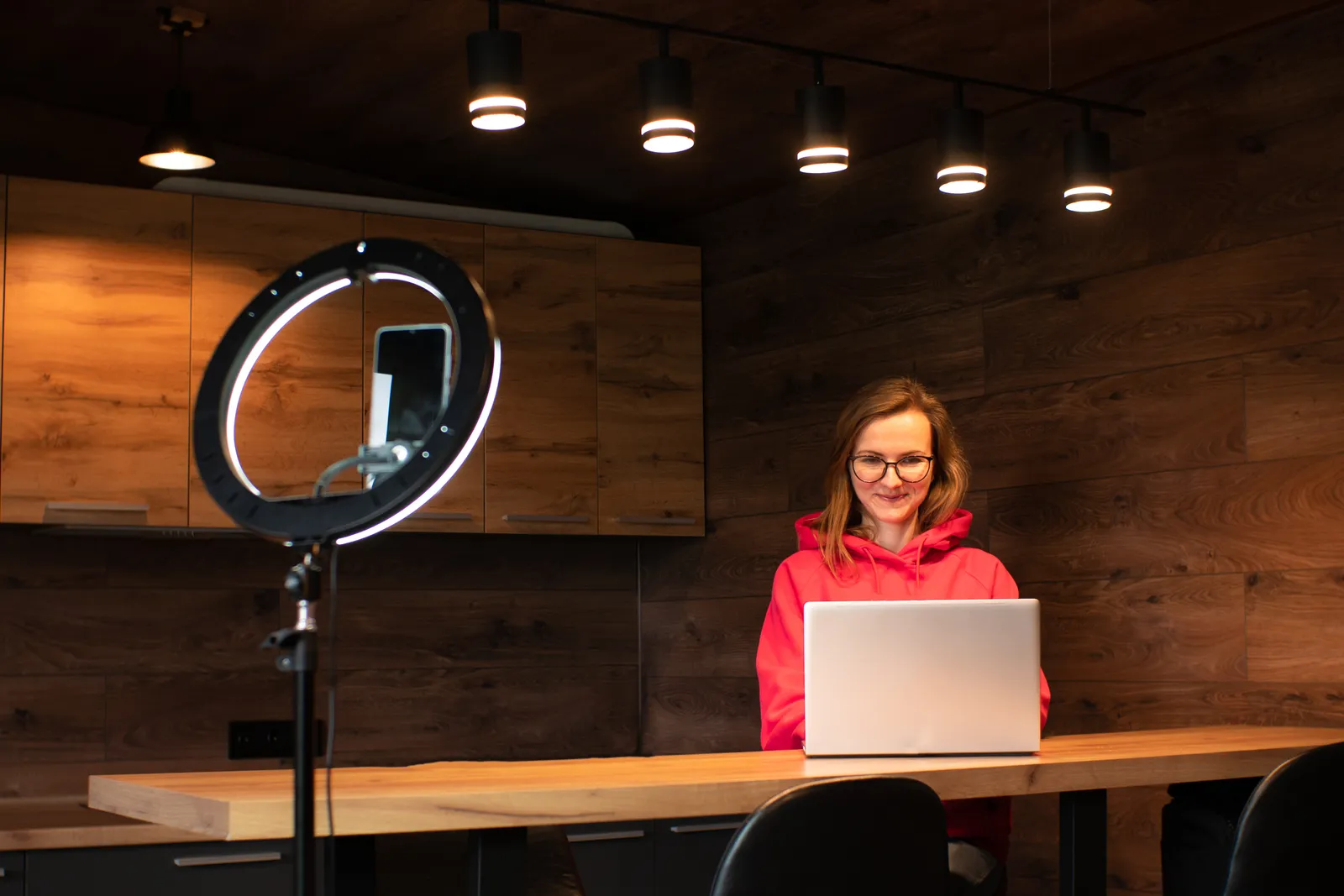 Creator working at a laptop beside a ring light in a studio