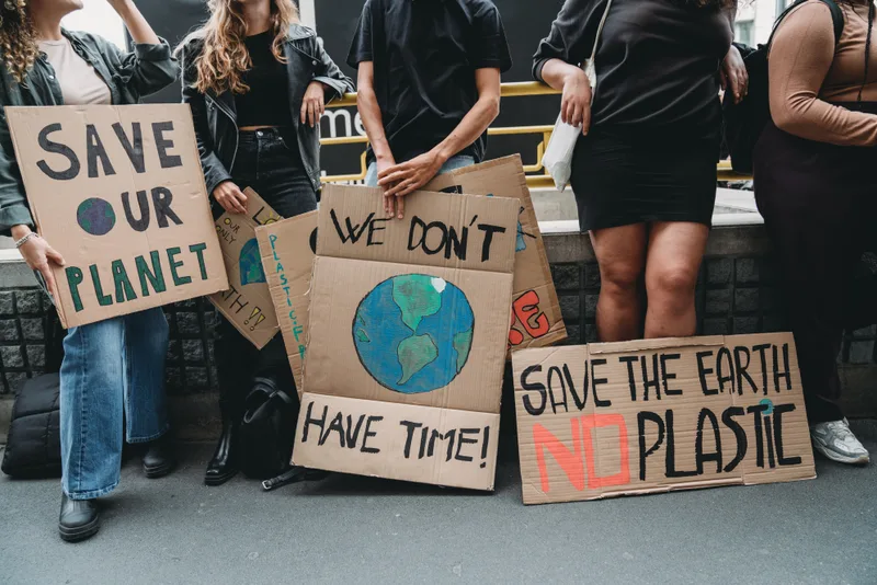 Marchers holding hand-painted cardboard signs reading 'Save our planet' and 'We don't have time'