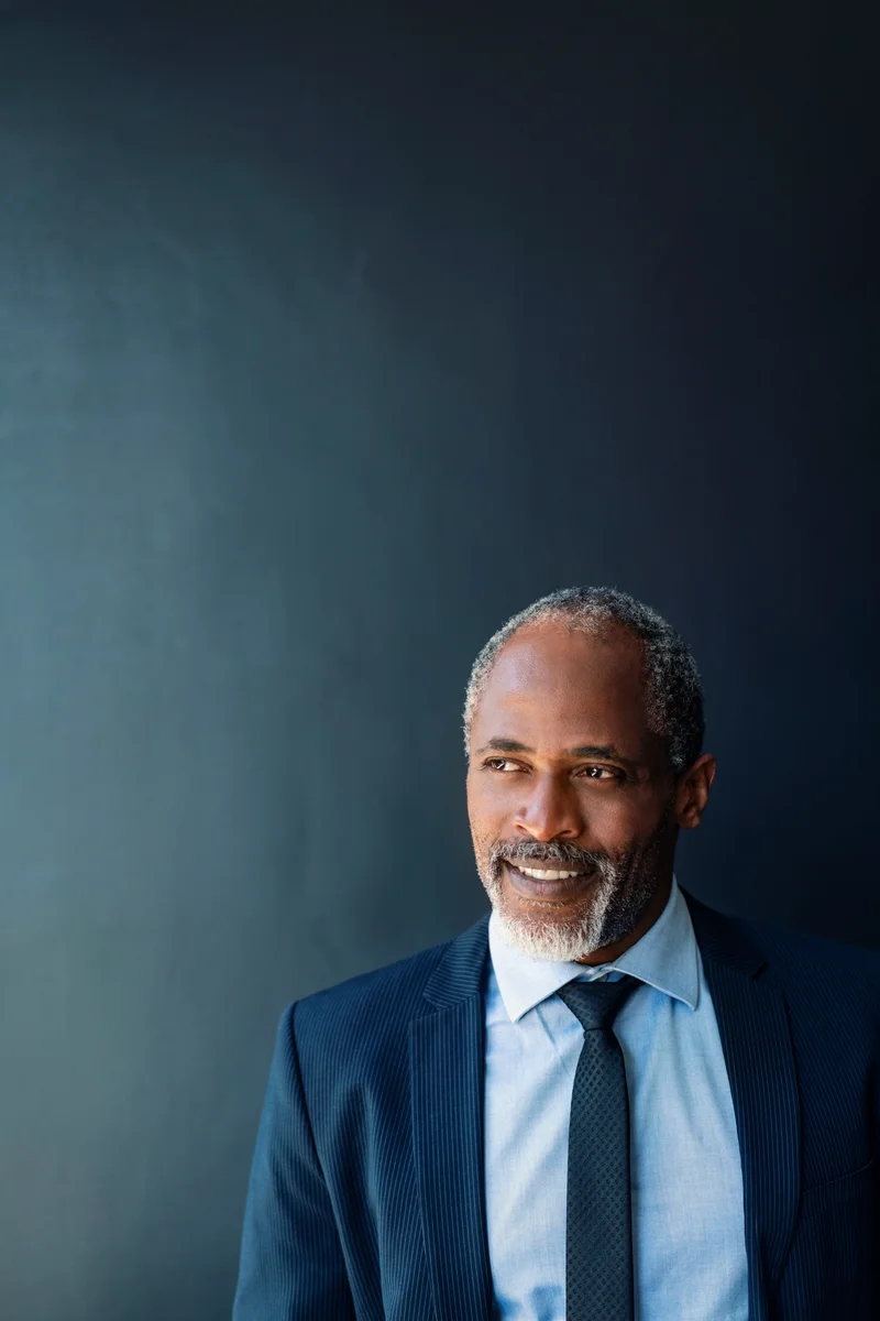 Marcus Ellison, Cardinal's founder and broker of record, in a navy suit against a dark studio background
