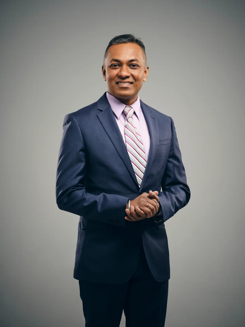 Arjun Mehta, Cardinal's new-construction lead, standing in a tailored suit and striped tie