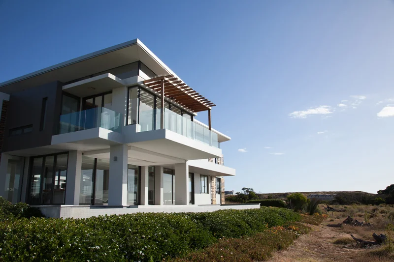 Modern white two-storey home at 128 Grand Flats Trail with wraparound balconies, overlooking protected meadow grasses