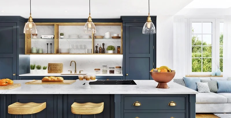 Navy-blue kitchen with a white marble island, brass hardware, pendant lights and wooden bar stools