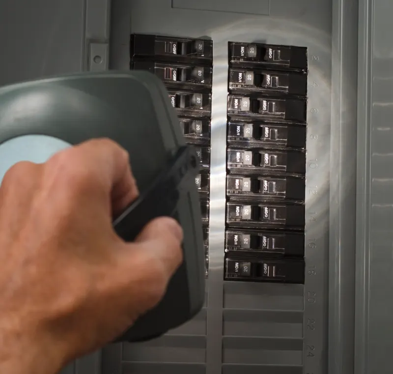Flashlight illuminating rows of circuit breakers inside an opened residential electrical panel