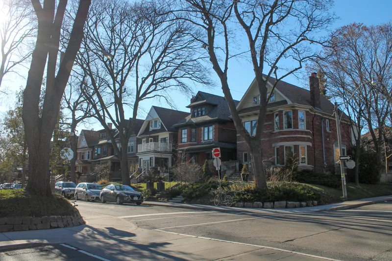 A tree-lined street of older two- and three-story brick homes on a sunny winter afternoon