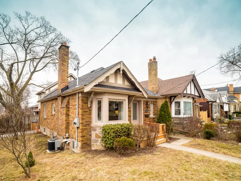 An older brick bungalow with a stone porch and a bay window on a quiet St. Louis street