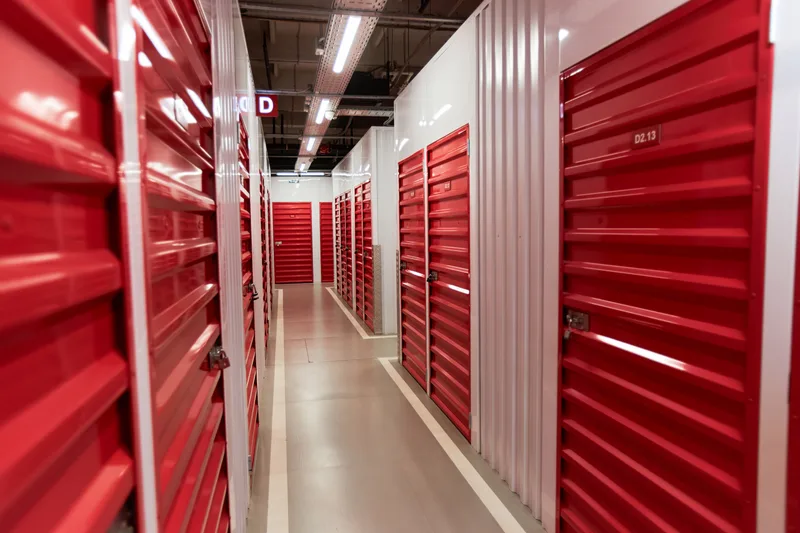 Bright indoor hallway of climate-controlled storage units with red roll-up doors