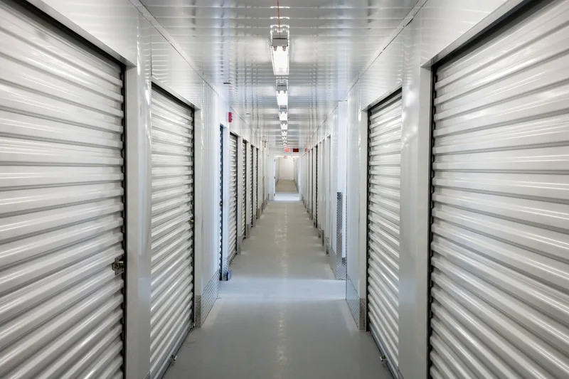 Long indoor storage hallway with white roll-up doors and polished concrete floor