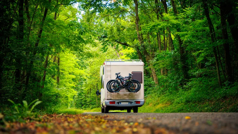 Motorhome with bikes on the back driving down a tree-lined road
