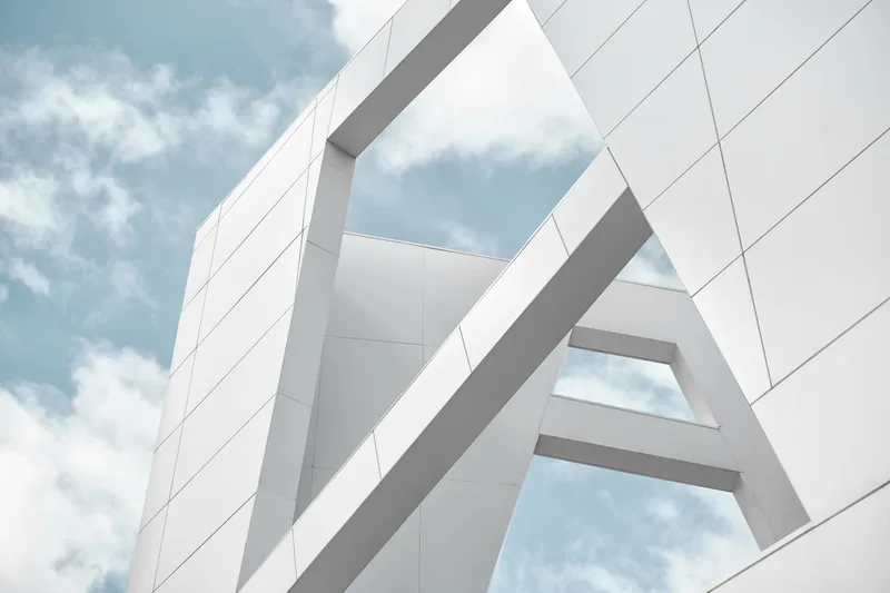 White architectural planes of the house intersecting against a blue sky with drifting clouds