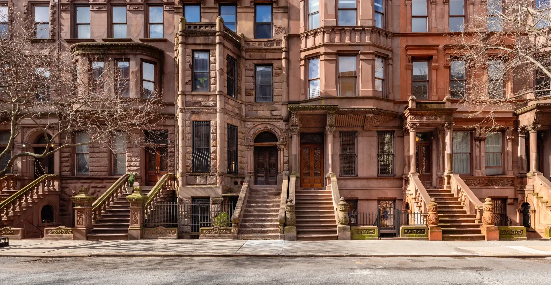 Row of ornate 19th-century brownstones on Rowan Terrace, carved stone stoops climbing to arched double doors