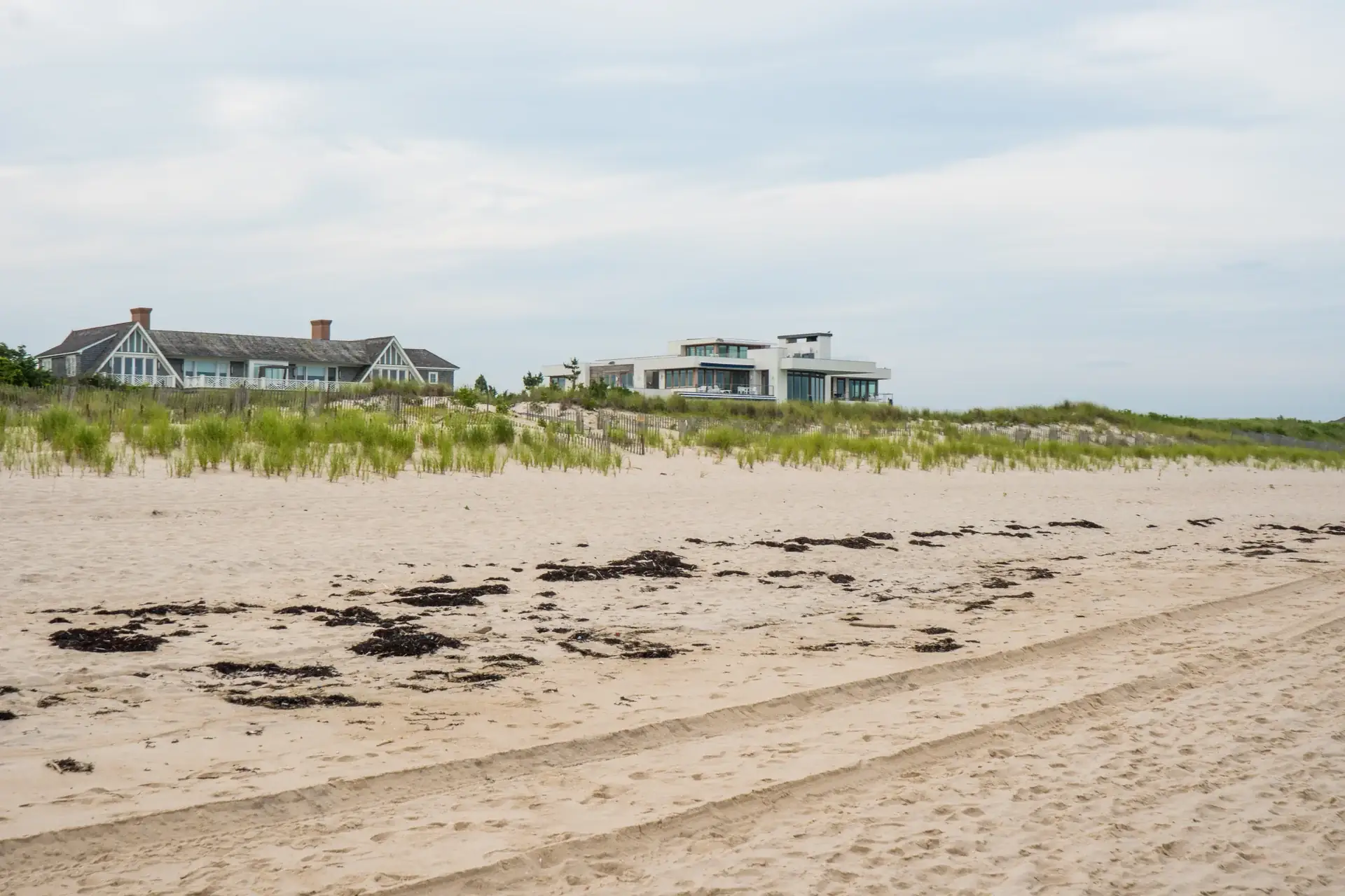 Dune Ridge seen across the beach — a gabled shingle house and its modern glass pavilion rising behind seagrass-covered dunes