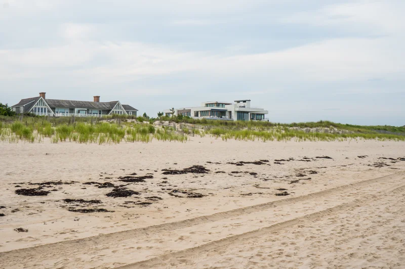 Dune Ridge seen across the beach — a gabled shingle house and its modern glass pavilion rising behind seagrass-covered dunes