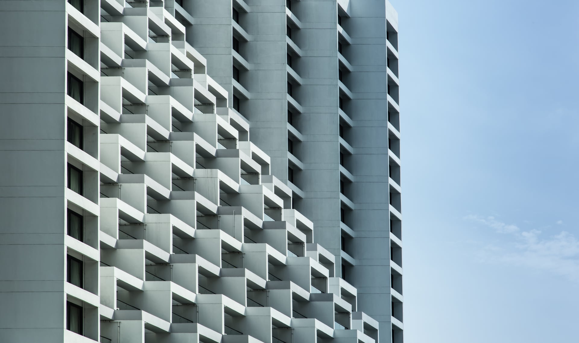 Tower facade of staggered white balconies stepping across the elevation in a diagonal rhythm against pale sky — artist's impression of the wind-sculpted west face.