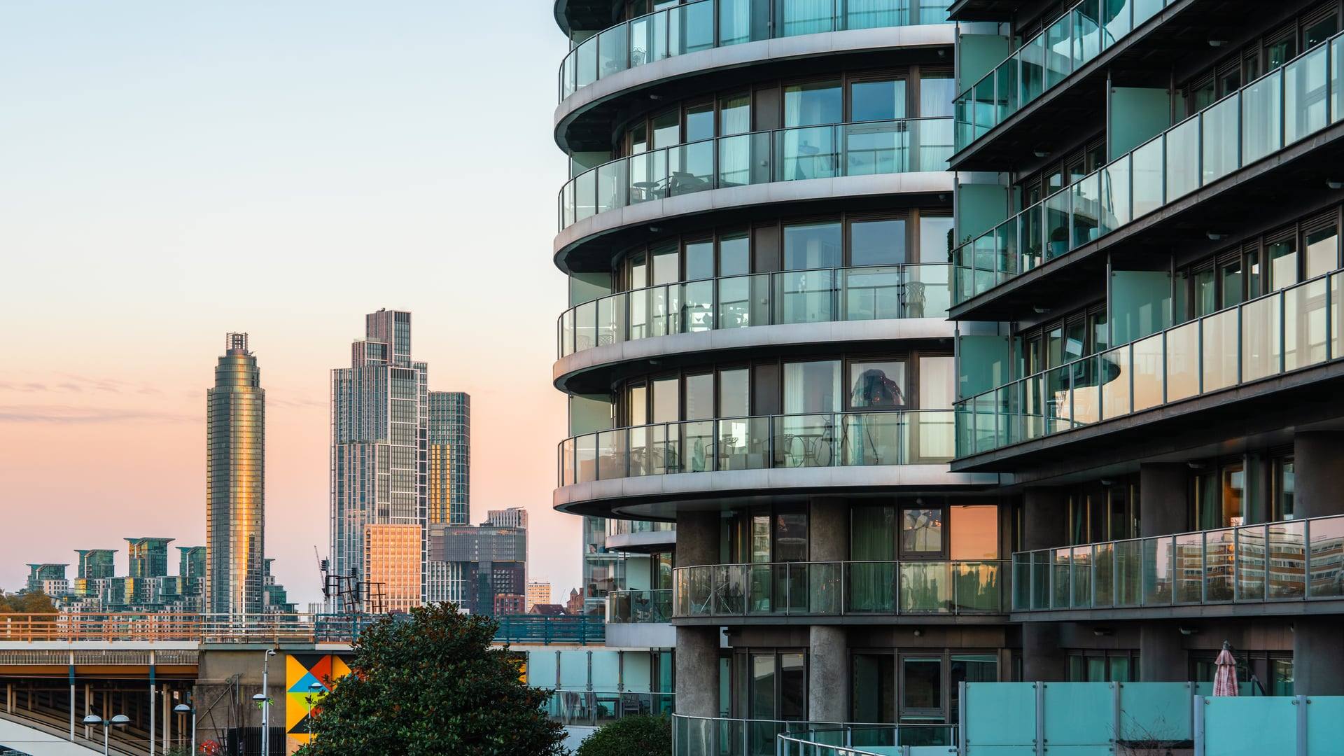 Curved glass residential tower at dusk, balconies glowing against a rose-grey skyline — artist's impression of The Westwind.