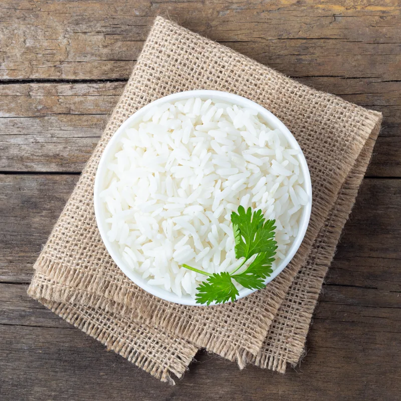 Bowl of steamed jasmine rice with a sprig of coriander, the base of the Miso Salmon bowl