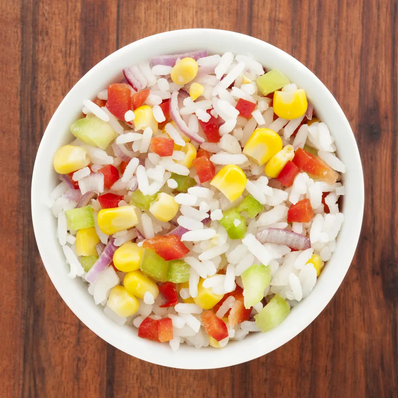 Citrus Chicken bowl base from above: jasmine rice tossed with charred corn, red peppers, and red onion in a white bowl