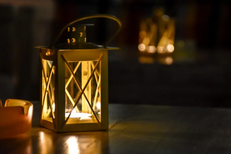 A small brass lantern glowing on a dark wooden table at Brassica, a second one blurred in the background