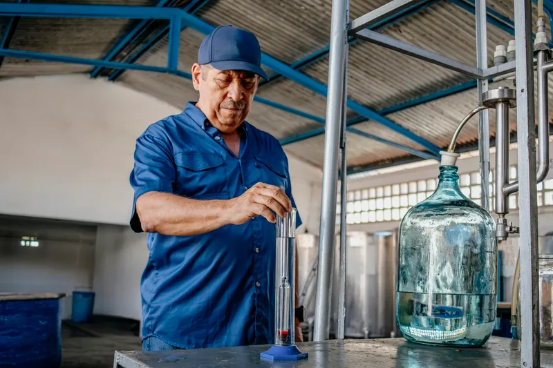 A distiller checks the strength of a new spirit with a glass hydrometer