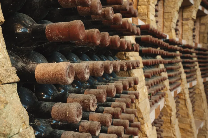 Dusty older bottles resting on their sides in a stone cellar