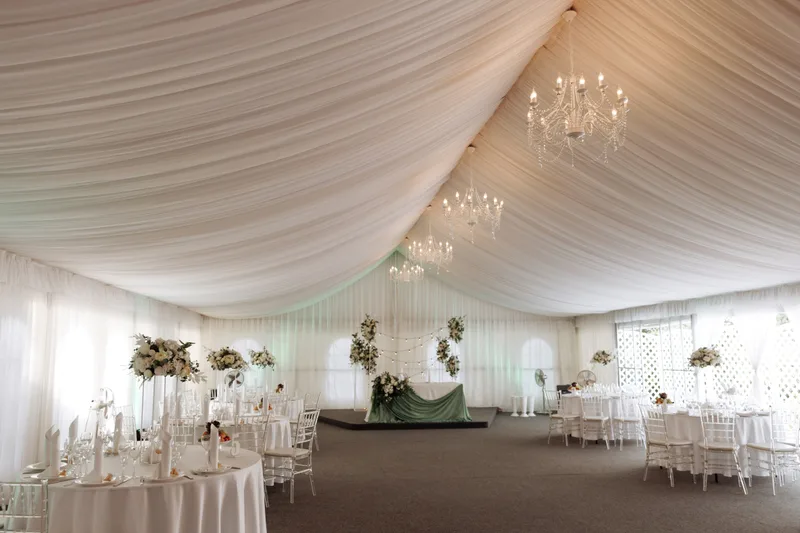 Inside a white tent set with round tables for a reception