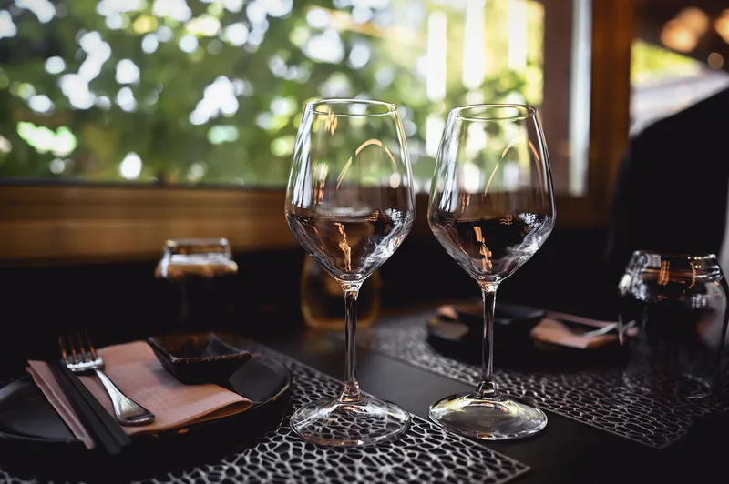 Two wine glasses on a dark table set for an evening event