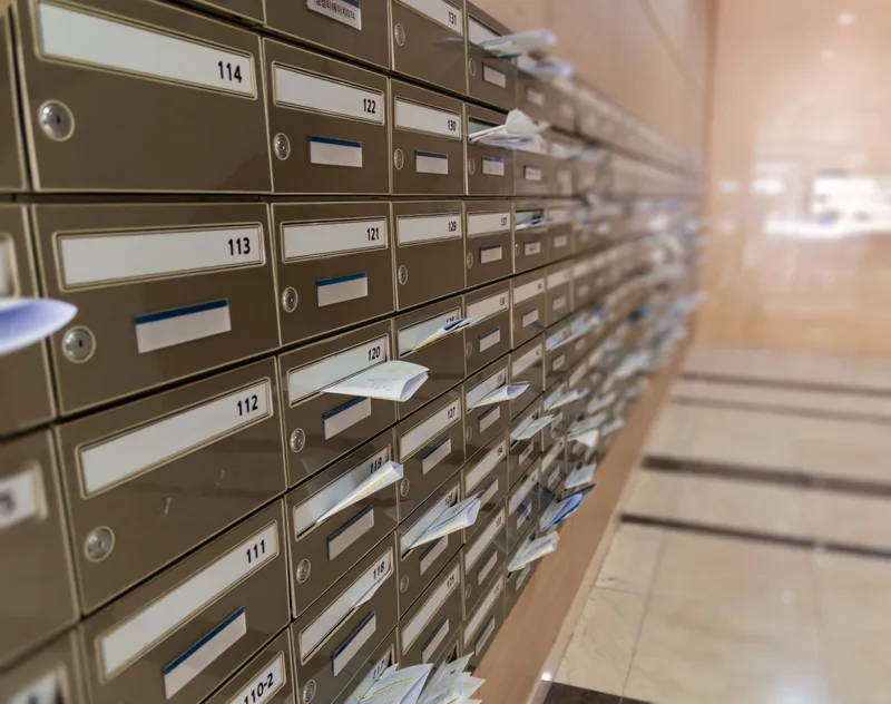 A long wall of numbered metal mailboxes in an apartment building lobby