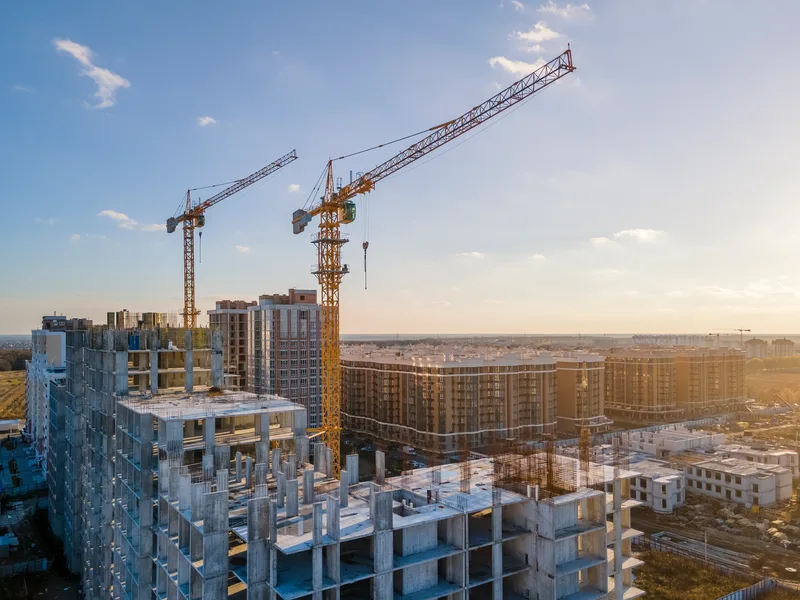 Aerial view of tower cranes over concrete frames of a mid-rise project at sunset