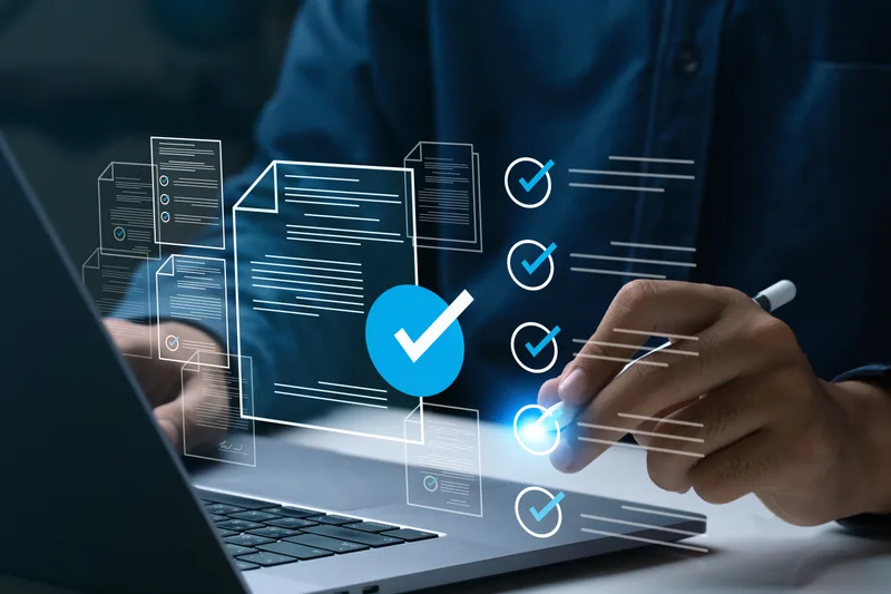 Hands at a laptop reviewing a floating checklist of audit documents with completed checkmarks